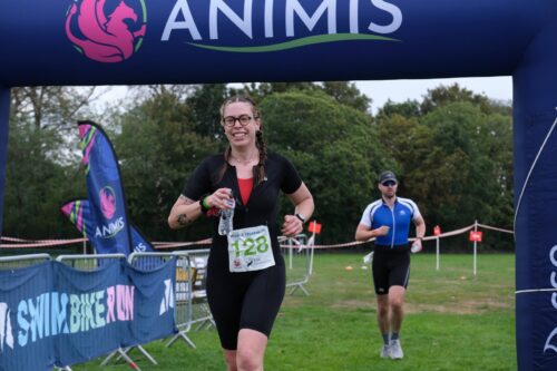 A first-time triathlete finishing under the Animis arch at Crowle Triathlon